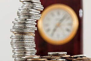 Stack of coins with clock in background